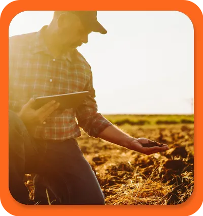 farmer with a handful of soil holding a tablet